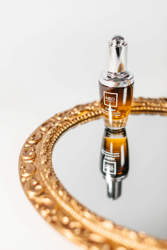 C-Major Serum bottle by Neo Naturelle, reflected on a gold ornate mirror—showcasing the star ingredient, THDA, for menopausal skin.